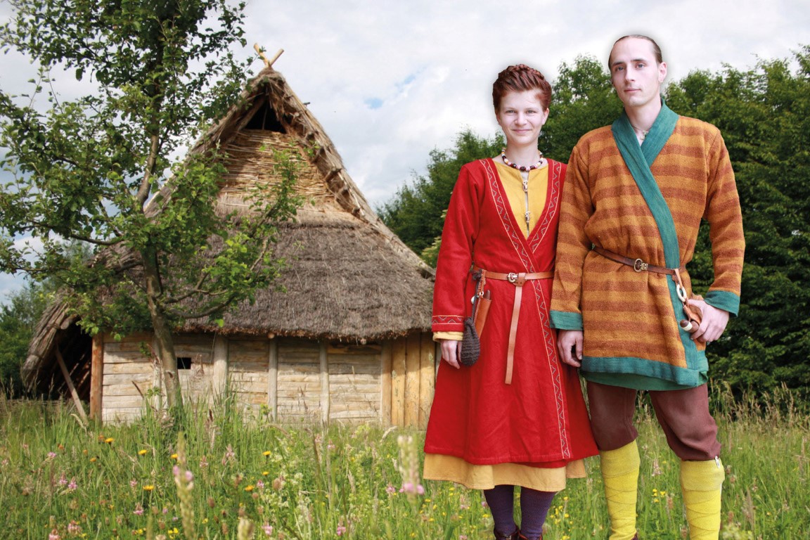 Bajuwarenpaar in farbenprächtiger Kleidung vor einem typischen Wohnhaus aus dem 5. Jahrhundert. Photo Credit: djd | Stadt Ellwangen